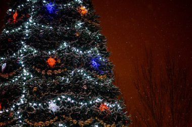 Şehir meydanında büyük bir Noel ağacı kışın aydınlık ve süslemelerle