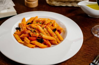 Domatesli spagetti makarna ve ahşap masa üzerinde maydanoz. Domates soslu makarna, taze fesleğen ve kızarmış domates.