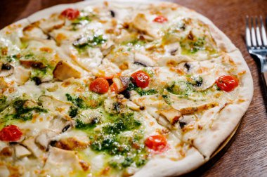 Tavuk, mozarella, zeytin ve fesleğen soslu pizza. Tahta arka planda tavuk ve turşulu pizza.