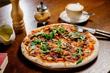 Ekstra mozarella peynirli mantar pizzası ve ahşap bir masa üzerinde otlar. En iyi manzara. İtalyan fast food. Lezzetli sıcak pizza dilimlendi ve ahşap tabakta malzemelerle servis edildi.
