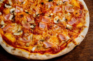 Ekstra mozarella peynirli mantar pizzası ve ahşap bir masa üzerinde otlar. En iyi manzara. İtalyan fast food. Lezzetli sıcak pizza dilimlendi ve ahşap tabakta malzemelerle servis edildi.