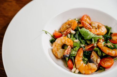 Karides, domates ve ahşap arka planda karışık sebzeli taze salata tabağı. Sağlıklı yemek. Sağlıklı salata tabağı. Taze deniz ürünleri tarifi. Izgara karides ve taze sebze salatası.