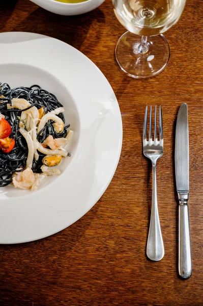Zwarte spaghetti. Pittige Zwarte zeevruchten pasta met inktvis met basilicum op houten tafel. — Stockfoto