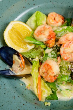İstiridyeli salata, karides ve sebze mavi tabakta ahşap arka planda, üst manzara