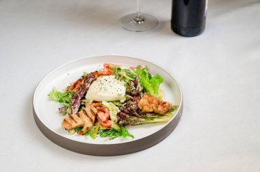 Kavurmalı Sezar salatası, bıldırcın yumurtası, kiraz domatesleri ve beyaz masada ızgara tavuk. Tavuk, fındık, yumurta ve sebzeli lezzetli salata..