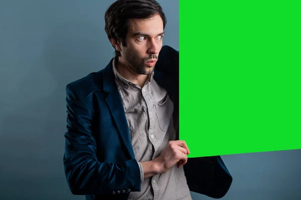 Surprised man holding green advertising banner.Surprised man with empty advertising banner. Man holds board for advertising. Handsome man with sign board. Space for text. Advertising. Black friday.