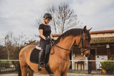 Binicilik okulunda ata binen bir kadın.