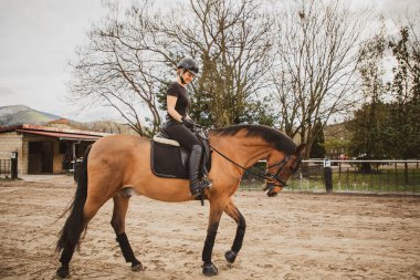 Binicilik okulunda ata binen bir kadın.