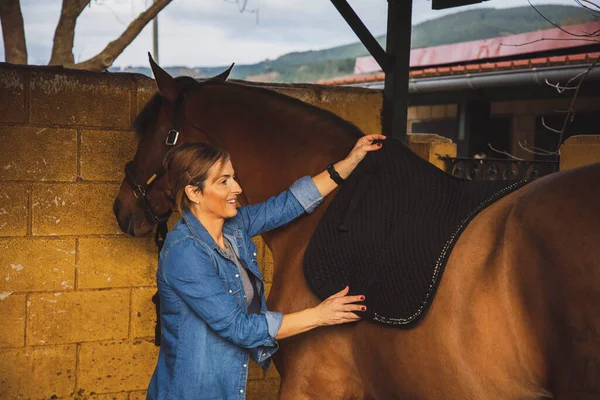 Kobieta Ubrana Dżinsy Buty Frędzlami Osiodłająca Konia Przygotowująca Jazdy — Zdjęcie stockowe