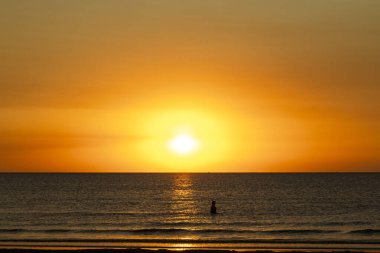 Sahile gidenler sakin bir sabah yüzüşü yaparken ve Kıbrıs 'ta güneş doğarken deniz kenarında yürürken, altın ışık kıyı şeridini yıkıyor..
