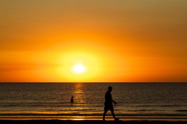 Sahile gidenler sakin bir sabah yüzüşü yaparken ve Kıbrıs 'ta güneş doğarken deniz kenarında yürürken, altın ışık kıyı şeridini yıkıyor..