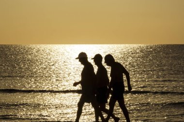 Aktif yaşlı yetişkinler, Kıbrıs 'ta huzurlu bir altın gün doğumu sırasında Akdeniz kıyısında sakin bir sabahın keyfini çıkarıyorlar..