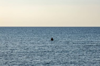 Kıbrıs Rum Kesimi 'nin sakin bir anında tek bir sığ sudaki tek bir figürle yalnızlık ve sükuneti çağrıştıran minimalist kıyı sahnesi.