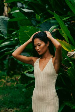 Güçlü ve zarif duruş ve kollar, bereketli bir doğal ortamda egzotik yapraklar arasında kaldırıldı.