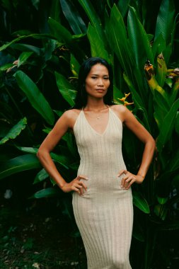 Cesur duruş ve nötr tonlar, bu tropikal moda esinlenilmiş sahnede canlı yeşillikle tezat oluşturuyor.