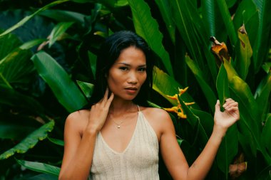 Güçlü bakışlar ve modern tasarım doğal yeşil yapraklar ve egzotik çiçeklerle çerçevelenmiştir.