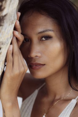 Yumuşak bir bakışla elini yanağına koyan bir kadının samimi portresi. Doğal güzellik ve dingin ruh hali.