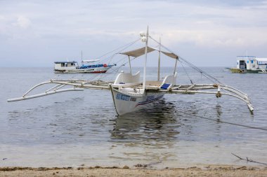 Yerel ulaşım ve ada kültürünü sembolize eden sığ kıyı sularında uzanan beyaz bir banca