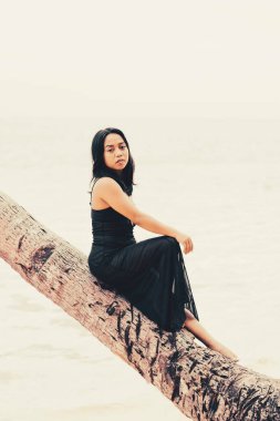 Kıyı şeridinde düşmüş bir palmiyeye oturmuş rahat bir kadının monokrom hayat tarzı portresi özgünlüğünü, sükunetini ve zahmetsiz sahil zarafetini ifade ediyor..