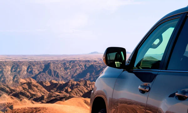 Close-up of a vehicle in the sand before a cliff.  Moon valley. Africa. Namibia