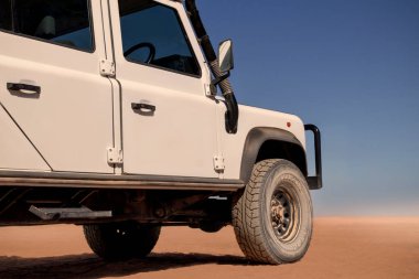 Güneşli bir günde Namib Çölü 'nün kırmızı kumlarında beyaz bir araba duruyor. 23.08.2021. Sossusvlei, Namibya