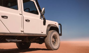 Güneşli bir günde Namib Çölü 'nün kırmızı kumlarında beyaz bir araba duruyor. 23.08.2021. Sossusvlei, Namibya