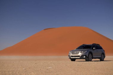 Subaru Outback, Namib Çölü 'nün ortasında Sossusvlei' nin kırmızı kum tepeciğinin yanında duruyor.. 