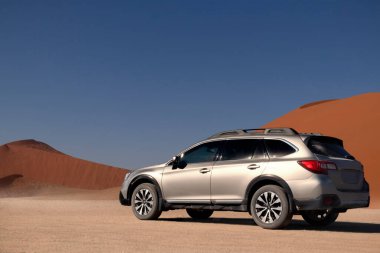 Subaru Outback, Namib Çölü 'nün ortasında Sossusvlei' nin kırmızı kum tepeciğinin yanında duruyor.. 