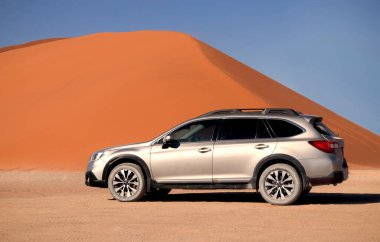Subaru Outback, Namib Çölü 'nün ortasında Sossusvlei' nin kırmızı kum tepeciğinin yanında duruyor.. 