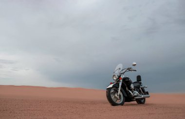 Canlı bir günbatımı gökyüzünün altında park etmiş bir motosiklet, özgürlük, macera ve bağımsızlığı çağrıştırıyor, ve açık yolların ruhunu yansıtıyor, kişisel keşifler, ve ufkun ötesine geçmek için sonsuz arzu..