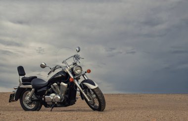 Canlı bir günbatımı gökyüzünün altında park etmiş bir motosiklet, özgürlük, macera ve bağımsızlığı çağrıştırıyor, ve açık yolların ruhunu yansıtıyor, kişisel keşifler, ve ufkun ötesine geçmek için sonsuz arzu..