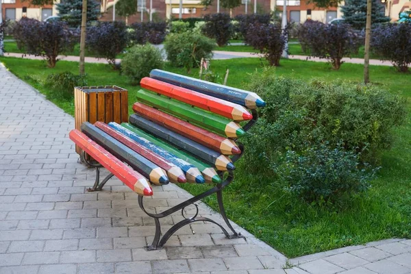 Erős modern városi utcai keményfa bútor. Kreatív sokszínű fa pad készült táblák stilizált színes ceruzák gyermekjátszótéren nyilvános parkban. — Stock Fotó