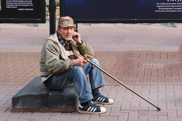 Frustrato uomo anziano triste con bastone seduto sulla strada in solitudine e guardando la fotocamera. Povertà e disperazione, concetto di Social Pension Problem. Mosca, Russia, settembre 2020 — Foto Stock
