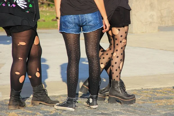 Teenagers Urban Diversity Lifestyle.Casual Youth Subculture Style Concept.Trio of trendy screaming girls wearing holey tights and shabby boots on big city street.Women legs dressed in ripped stockings