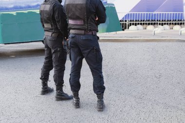 Polis memurlarının siyah üniforma giyip telsizle sokaklarda devriye gezerken ki görüntüsü. Şehri kontrol eden askeri birliğin güvenlik görevlileri. Polis pantolonu ve modern tasarım botları..