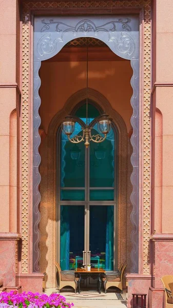 Abu Dhabi, Emirati Arabi Uniti, marzo 2021.Tavolo e sedie in terrazza all'aperto caffè sotto il tradizionale arco di vetro decorato design in stile arabo con intagliato artigianalmente sul marmo dal lato cortile nel lussuoso Emirates Palace. — Foto Stock