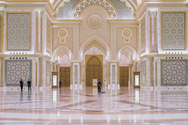 Abu Dhabi, BAE, Mart 2021 Büyük Salon 'daki mermer temizleme işçisi Arap tarzında yeni lüks başkanlık sarayı Qasr Al Watan' ın süslemeleri, güvenlik görevlilerinin bulanık arka planda olması..