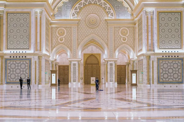 Abu Dhabi, Emiratos Árabes Unidos, marzo de 2021.Limpieza de los trabajadores lavando el suelo de mármol en el Gran Salón adornado estilo árabe del nuevo y lujoso Palacio Presidencial, Qasr Al Watan, con el equipo de guardia de seguridad sobre un fondo borroso. Fotos de stock