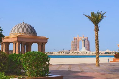 Abu Dabi manzaralı gökdelenli lüks Fairmont konutları ve Emirates Sarayı otelinin avlusundan palmiye ağaçlı dekoratif plaj çardağı. Bu Dabi, BAE, Mart 2021
