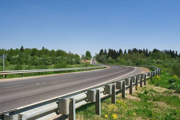 Leere asphaltierte Landstraße, die sich durch Ackerland und Wald schlängelt. Hintergrund Straße. — Stockfoto