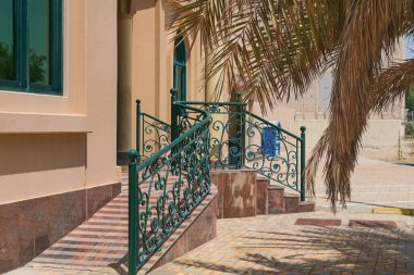 Bebek arabaları ve tekerlekli sandalye kullanıcıları tarafından kolay erişim için merdivenleri ve yumuşak rampası olan süslü, sahte çiçek desenli sundurması..