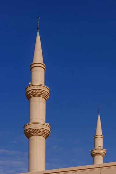 Minaret muslimské islámské mešity na pozadí modré oblohy. Minaretní věž s tradičním půlměsícem, artefakturálními dekorativními prvky. — Stock fotografie