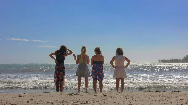 Achteraanzicht naar een groep van vier vriendinnen in strandkleding die op het strand staan en ver weg samen kijken. Meisjes tieners team hebben plezier op het strand. SOFT FOCUS foto. Mauritius, Afrika, juli 2014 — Stockfoto