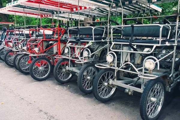 Során vintage pedál-power négykerekű surrey kerékpár kiadó parkolási nyilvános parkban. Retro quad kerékpár kölcsönző állomás. Környezetbarát utcai közlekedés, egészséges életmód, városi környezet. — Stock Fotó