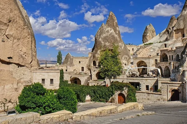 Travel to fairy Cappadocia. Street with restaurants and cave hotels carved inside stone rock at sunny day in old town Goreme. Cappadocia, Nevsehir Province, Central Anatolia, Turkey
