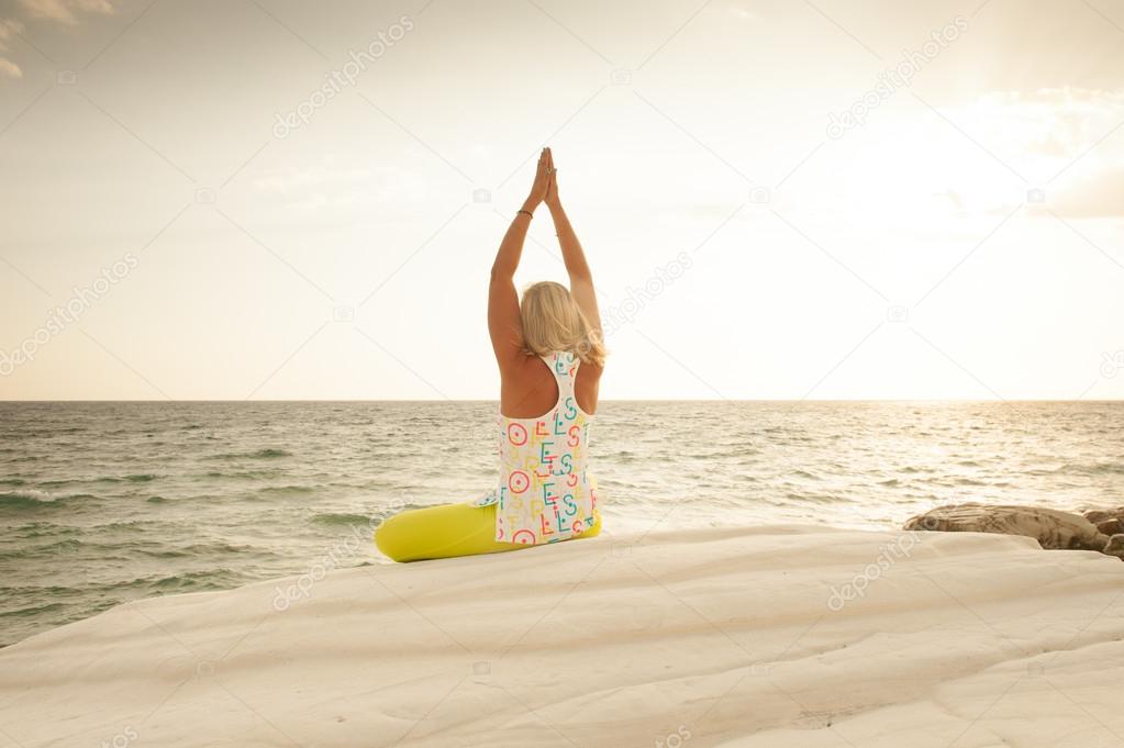 Young woman is meditating by the sea