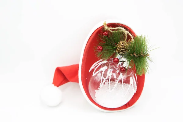 Прозрачная Стеклянная Рождественская Ёлка Лежит Шляпе Санта Клауса Изолированной Белом — стоковое фото