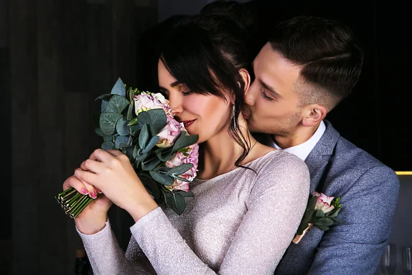 Der Mann Umarmt Und Küsst Ein Mädchen Mit Einem Rosenstrauß — Stockfoto