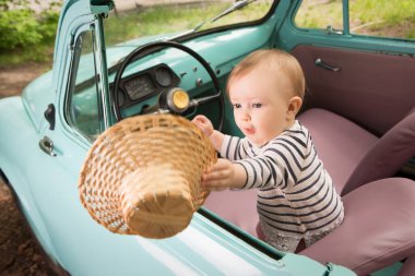 Küçük güzel çocuk açık çatılı bir arabada araba sürerken şapkasını rüzgarda yakalıyor. Komik gezgin..