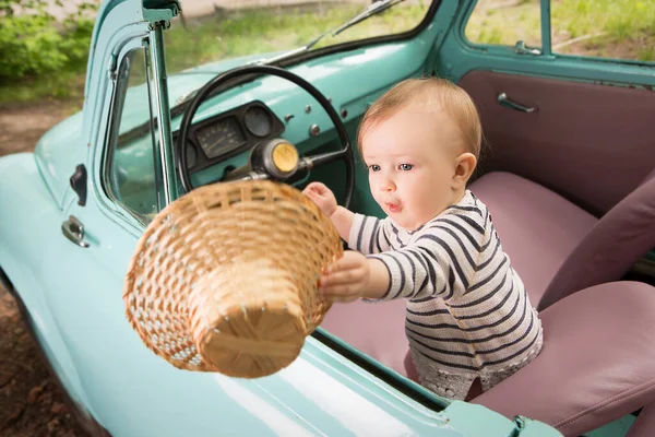 Küçük güzel çocuk açık çatılı bir arabada araba sürerken şapkasını rüzgarda yakalıyor. Komik gezgin..